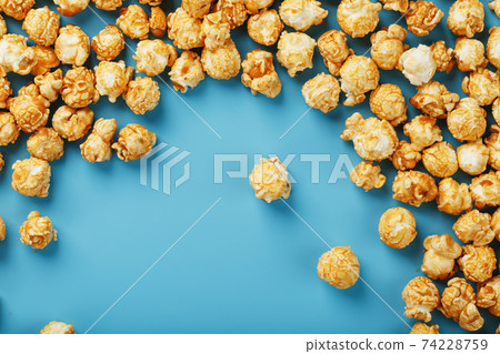 Caramel popcorn by a ripple on a blue background, in the form of a frame. 74228759