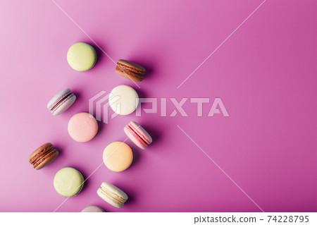 Colorful French macaroni cookies are scattered on a pink background. 74228795