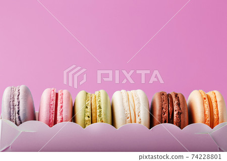 Colorful French macarons cookies in a package on a pink background. 74228801