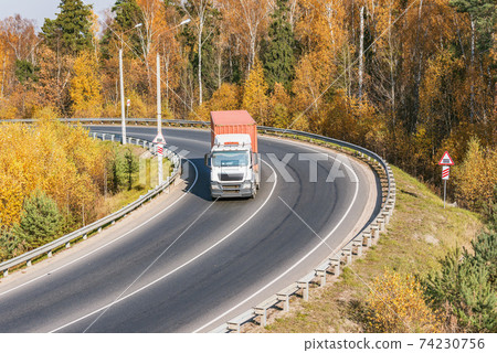 Freight truck moves on the road at autumn day. Freight truck moves on the road at autumn day. 74230756