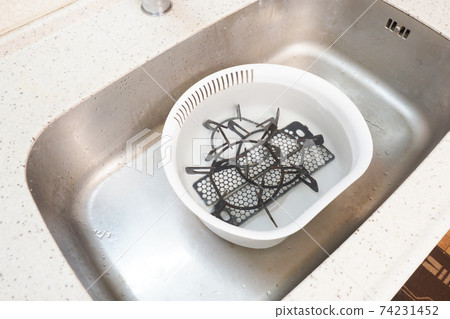 A trivet and a gas range cover in a washing tub filled with water A trivet and a gas range cover in a washing tub filled with water 74231452