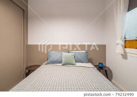 Interior of new small bedroom with wardrobe and window. Calm colors and quality bed linen 74232490