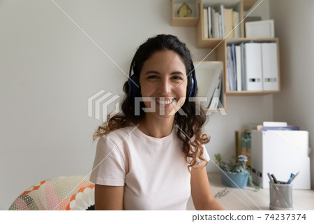 Headshot portrait of happy young woman wearing headset at home Headshot portrait of happy young woman wearing headset at home 74237374