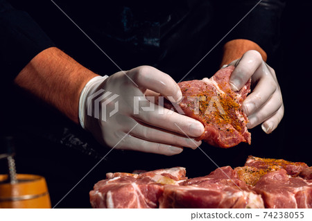 Marinating pork neck skewers, adding salt, curry and basil to the meat, pieces of meat on a wooden board. 74238055