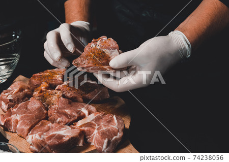 Marinating pork neck skewers, adding salt, curry and basil to the meat, pieces of meat on a wooden board. Marinating pork neck skewers, adding salt, curry and basil to the meat, pieces of meat on a wooden board. 74238056