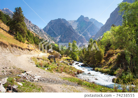 The natural landscape of mountains in Tajikistan on a sunny bright day. Amazing view on Fann mountains with mountain stream near hiking trail. 74238555