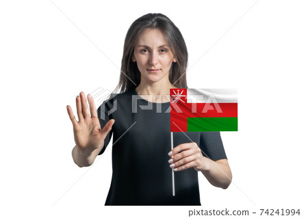 Happy young white woman holding flag of Oman and with a serious face shows a hand stop sign isolated on a white background Happy young white woman holding flag of Oman and with a serious face shows a hand stop sign isolated on a white background 74241994