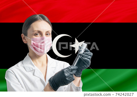 Girl doctor prepares vaccination against the background of the Libya flag. Vaccination concept Libya Girl doctor prepares vaccination against the background of the Libya flag. Vaccination concept Libya 74242027