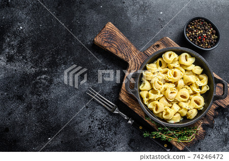 Italian tortellini pasta with cheese sauce in a pan. Black background. Top view. Copy space Italian tortellini pasta with cheese sauce in a pan. Black background. Top view. Copy space 74246472