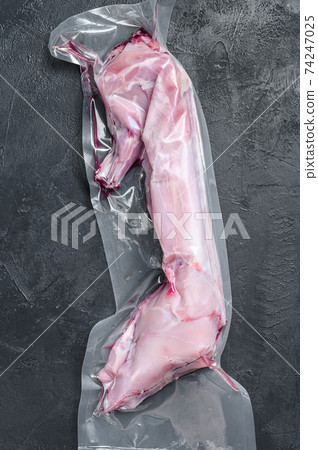 A whole raw rabbit in a vacuum package. Black background. Top view A whole raw rabbit in a vacuum package. Black background. Top view 74247025