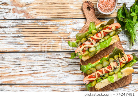 Various hot dog with vegetables, lettuce and condiments. White wooden background. Top view. Copy space 74247491