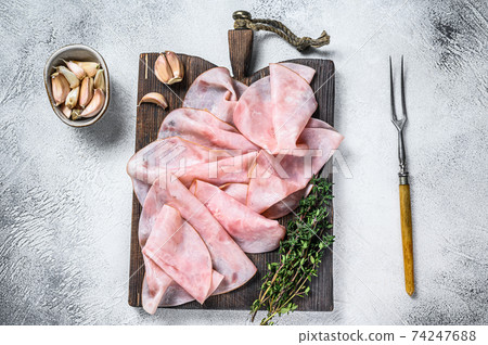 Ham Thin sliced on wooden cutting board with herbs. White background. Top view Ham Thin sliced on wooden cutting board with herbs. White background. Top view 74247688