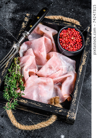 Thin sliced Smoked pork ham in wooden tray. Black background. Top view Thin sliced Smoked pork ham in wooden tray. Black background. Top view 74247815