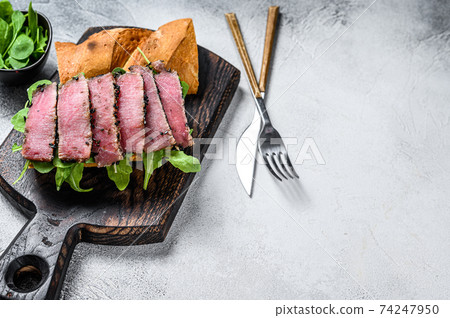 Tuna steak sandwich in a baguette with arugula. White background. Top view. Copy space Tuna steak sandwich in a baguette with arugula. White background. Top view. Copy space 74247950