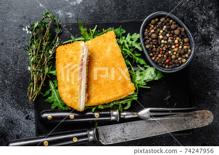 Fried cordon bleu meat chicken cutlet with ham and cheese. Black background. Top view Fried cordon bleu meat chicken cutlet with ham and cheese. Black background. Top view 74247956
