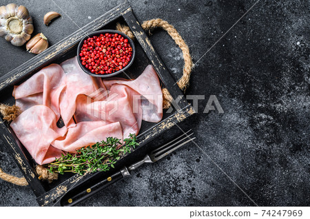 Thin sliced Smoked pork ham in wooden tray. Black background. Top view. Copy space Thin sliced Smoked pork ham in wooden tray. Black background. Top view. Copy space 74247969