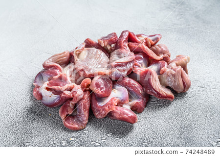Raw uncooked chicken gizzards, stomach. Gray background. Top view Raw uncooked chicken gizzards, stomach. Gray background. Top view 74248489