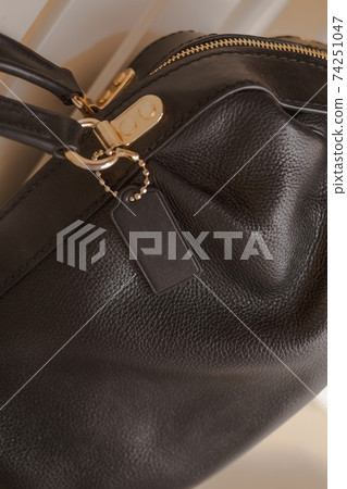 Black tag on genuine pebble leather bag with gold furniture 74251047