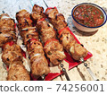 shish kebab on skewers on a plate and salsa sauce. 74256001