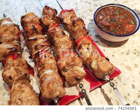 shish kebab on skewers on a plate and salsa sauce. 74256001