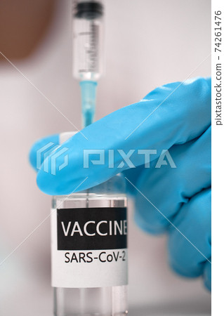 Doctor dials the vaccine into a syringe Doctor dials the vaccine into a syringe 74261476