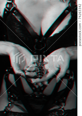 butt plug in the hands of a girl on the background of her Breasts in a bra and a leather belt 74263342