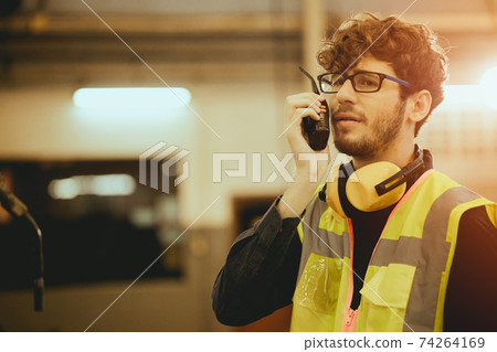 Young worker man using radio control communication in factory Young worker man using radio control communication in factory 74264169