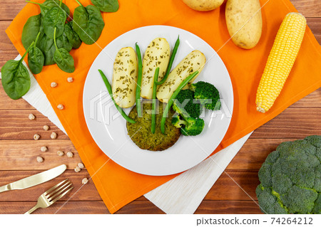 Top view of vegan burger or cutlet with baked potato, fresh green beans and vegetables on white plate 74264212
