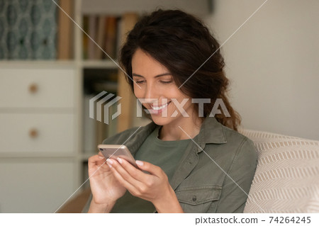 Smiling woman use cellphone browsing internet at home 74264245