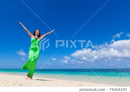 Woman in green dress on beach 74264293
