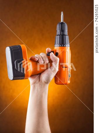 hand holding a screwdriver on an orange background. hand holding a screwdriver on an orange background. 74265025