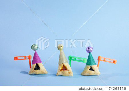 Purim celebration concept. Traditional Hamantashen cookies with clown hat and gragger. 74265136