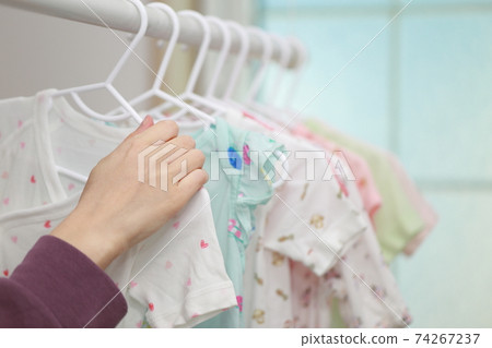 Mom preparing to give birth by watering baby clothes in the washing machine 74267237