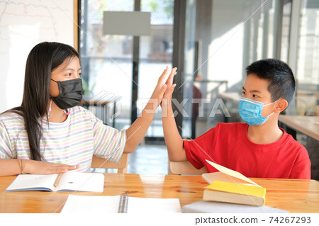 girl boy student friends wearing face mask giving high five at school 74267293