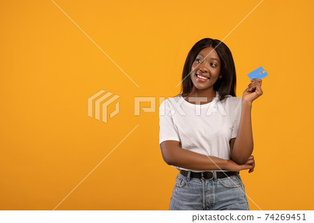 Smiling black woman with credit card looking at copy space Smiling black woman with credit card looking at copy space 74269451