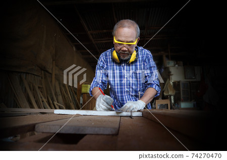 Carpenter, he is working in the workshop. Man at work on wood. Image of mature carpenter in the workshop, furniture making concept. 74270470
