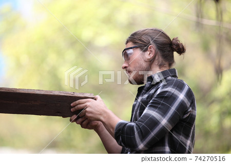 Carpenter, he is working in the workshop. Man at work on wood. Image of mature carpenter in the workshop, furniture making concept. 74270516