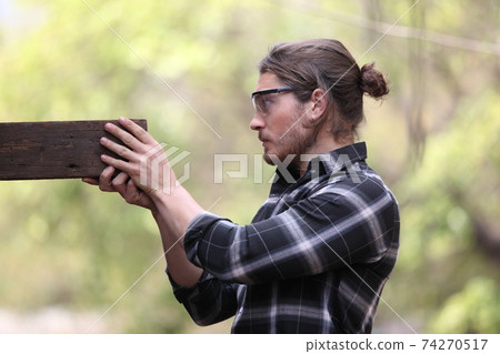 Carpenter, he is working in the workshop. Man at work on wood. Image of mature carpenter in the workshop, furniture making concept. 74270517
