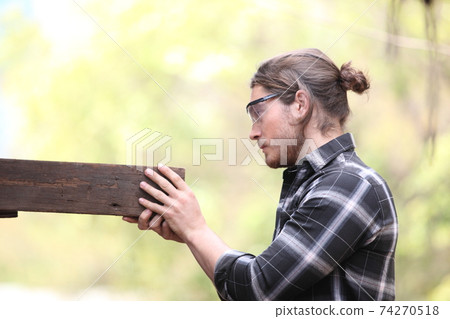 Carpenter, he is working in the workshop. Man at work on wood. Image of mature carpenter in the workshop, furniture making concept. 74270518