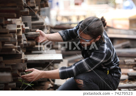 Carpenter, he is working in the workshop. Man at work on wood. Image of mature carpenter in the workshop, furniture making concept. 74270523
