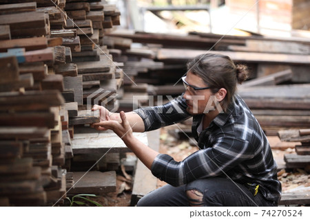 Carpenter, he is working in the workshop. Man at work on wood. Image of mature carpenter in the workshop, furniture making concept. 74270524