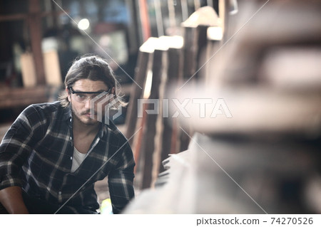 Carpenter, he is working in the workshop. Man at work on wood. Image of mature carpenter in the workshop, furniture making concept. 74270526