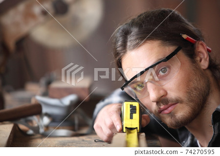 Carpenter, he is working in the workshop. Man at work on wood. Image of mature carpenter in the workshop, furniture making concept. 74270595