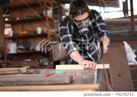 Carpenter, he is working in the workshop. Man at work on wood. Image of mature carpenter in the workshop, furniture making concept. 74270711