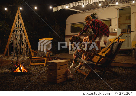 Man covers girlfriends in plaid by the campfire Man covers girlfriends in plaid by the campfire 74271264