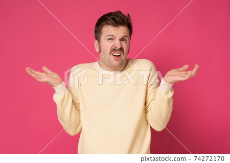 Young confused man shrugging shoulders, spreading hands isolated on pink background Young confused man shrugging shoulders, spreading hands isolated on pink background 74272170