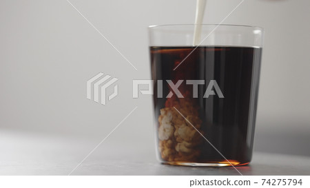 pour cream in cola in tumbler glass on concrete countertop with copy space 74275794