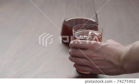 man hand take mulled wine in thin tumbler glass from walnut table 74275902