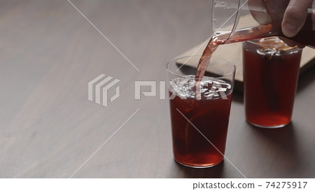 man hand serving mulled wine in thin tumbler glasses on walnut table 74275917