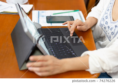 Businesswoman paying bills online using laptop at home. Businesswoman paying bills online using laptop at home. 74276226